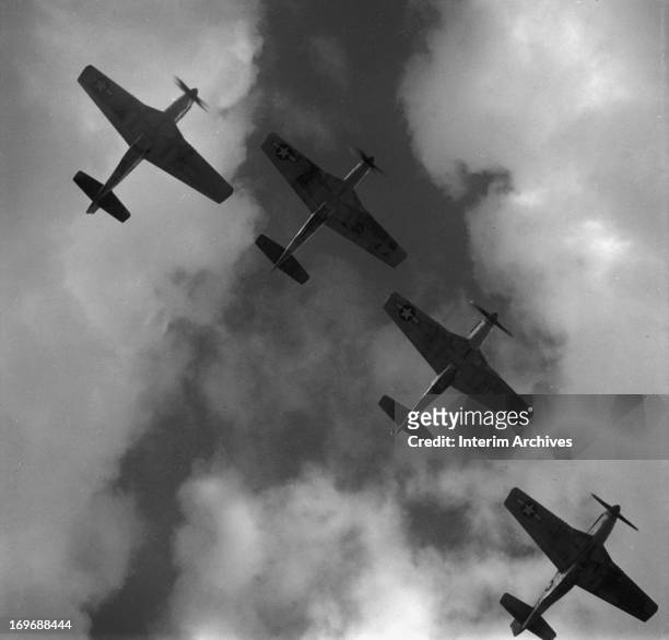 View, from below, of four P-51 Mustangs flying in formation, near Ramitelli airbase, in Italy, March 1945.