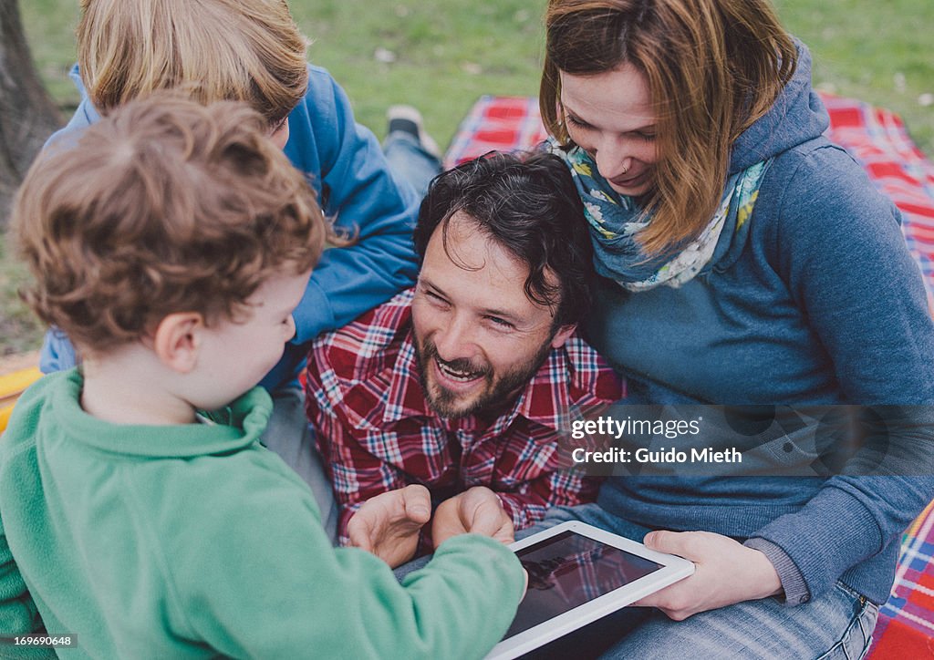 Happy family using tablet pc outdoor.