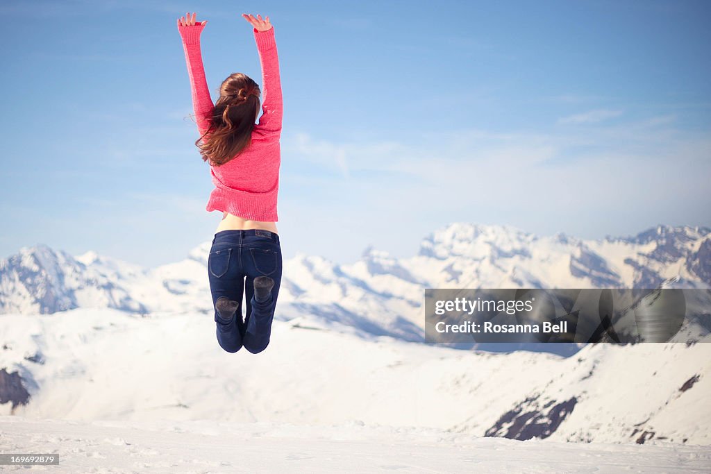 Girl jumping over swiss mountains