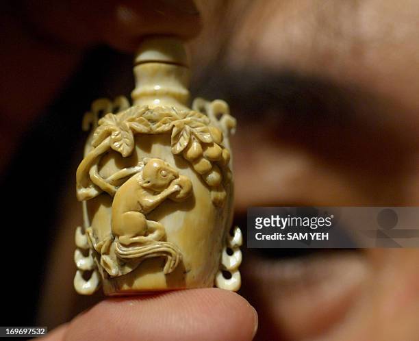 Man displays an ivory snuff bottle during an exhibition in Taipei on August 28, 2008. The snuff bottle was used to contain powdered tobacco and the...