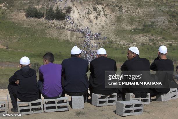 Residents of the Druze village of Majdal Shams in the Israeli-annexed Golan Heights watch as demonstrators gather along the Syrian border with Israel...