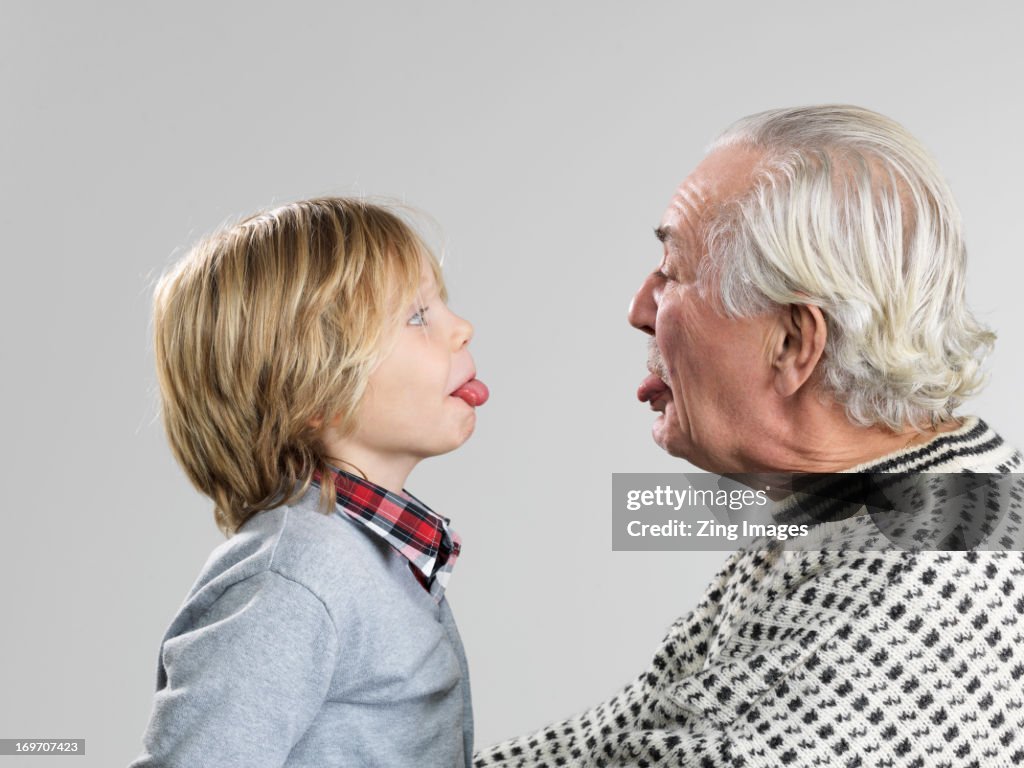 Boy and grandfather poking out tongues