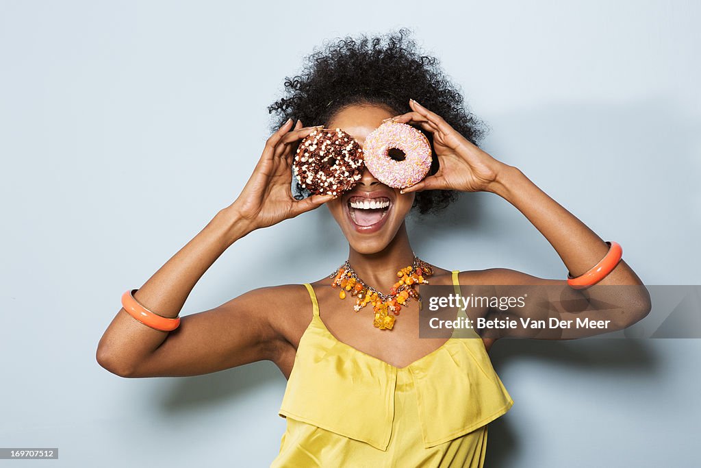 Woman holding different doughnuts in front of eyes