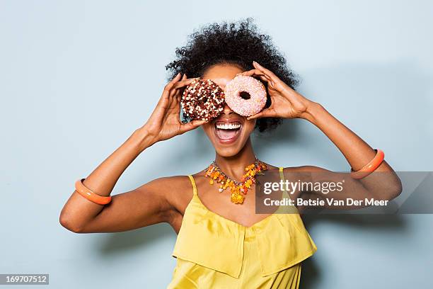 woman holding different doughnuts in front of eyes - women in see through tops stock pictures, royalty-free photos & images