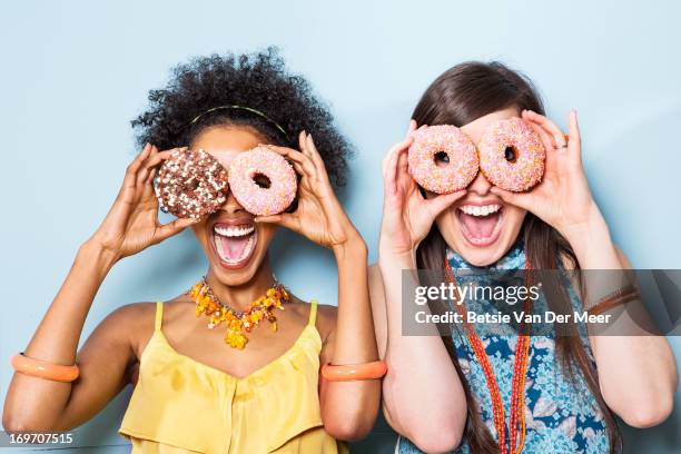 women holding doughnuts in front of eyes. - cuisine humour stock pictures, royalty-free photos & images