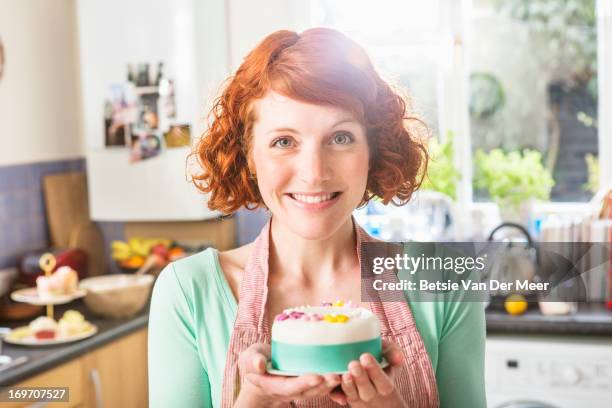 woman holding decorated icing cake, in kitchen. - woman front and back stock-fotos und bilder