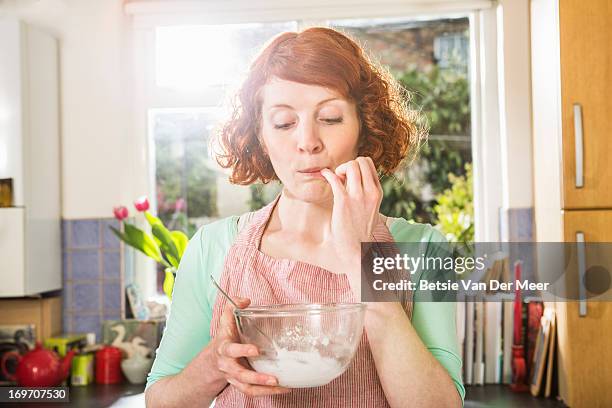 woman tasting icing for cakemaking. - finger in mouth stock pictures, royalty-free photos & images