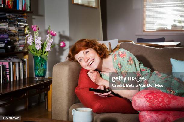 woman laughing while watching tv. - relaxing on sofa stock pictures, royalty-free photos & images