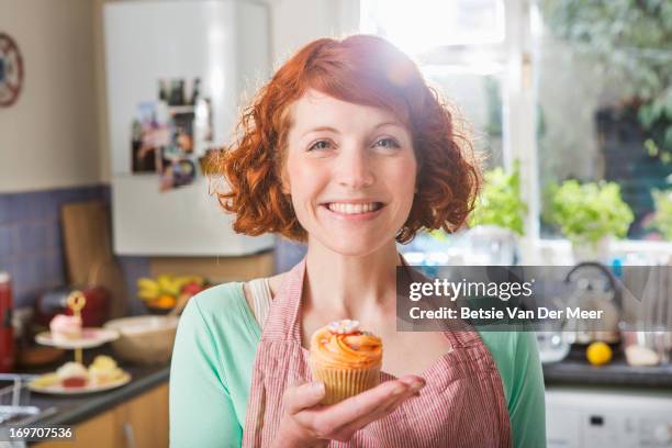 woman holding homemade cupcake smiling. - home made food stock pictures, royalty-free photos & images