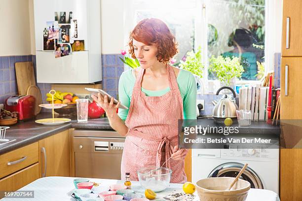 woman looking at digital tablet for baking recipe - baking reading recipe stockfoto's en -beelden