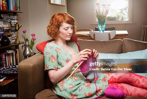 woman knitting, sitting in livingroom. - stitch stock pictures, royalty-free photos & images