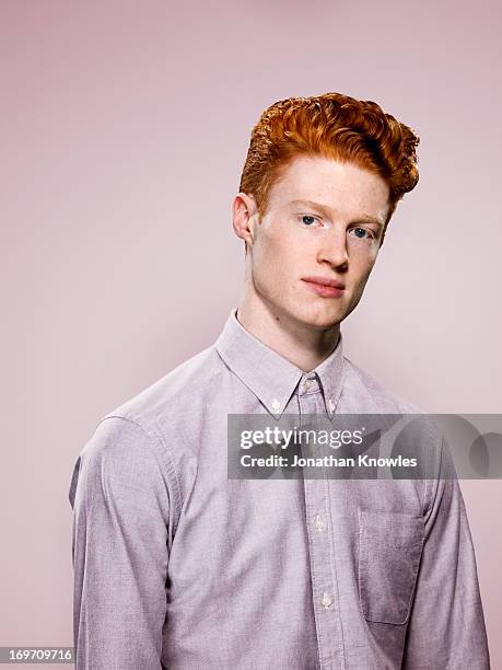 male with wavy red hair looking into camera - red shirt stockfoto's en -beelden