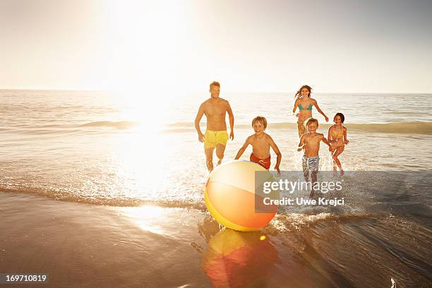 family playing with a beach ball by the sea - family beach holiday stock-fotos und bilder