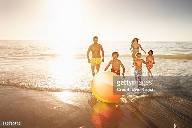 family playing with a beach ball by the sea - family beach vacation stock pictures, royalty-free photos & images