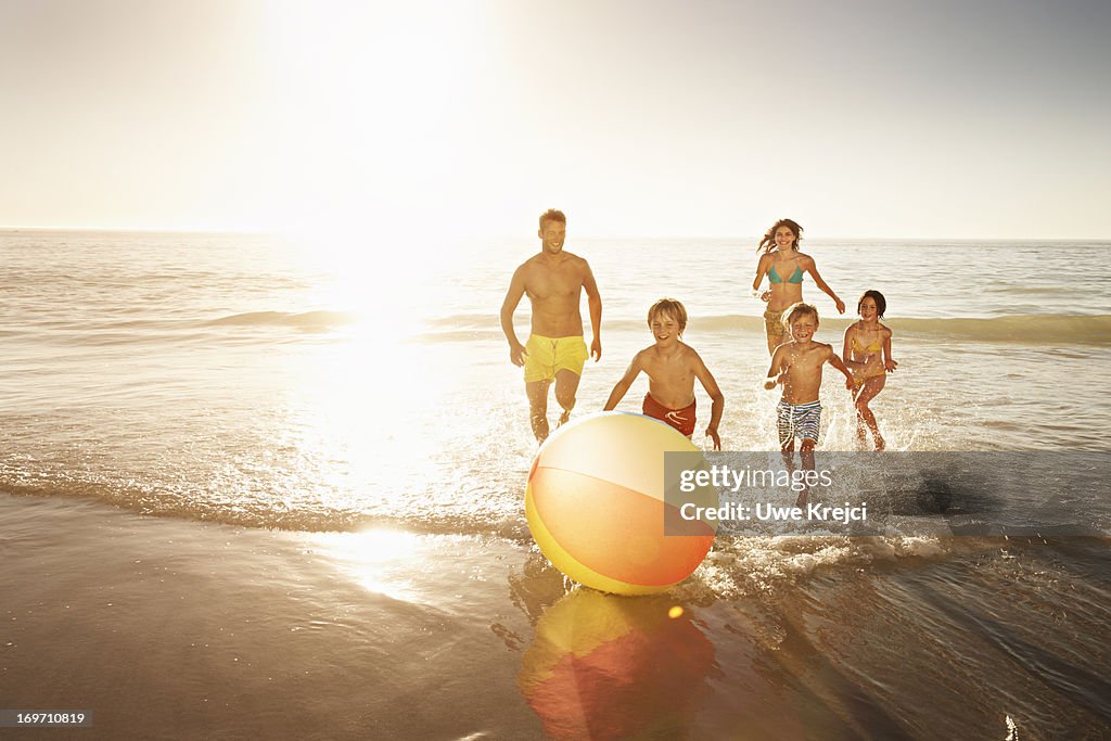 Family playing with a beach ball by the sea