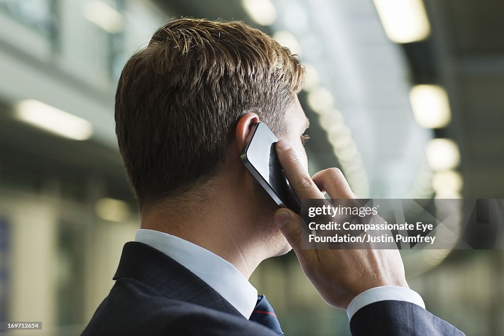 Businessman using mobile phone in office hallway
