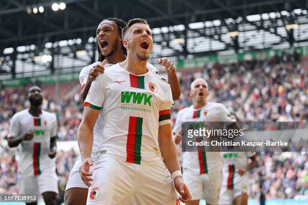 Ermedin Demirovic of FC Augsburg celebrates with teammates after scoring the team's second goal during the Bundesliga match between FC Augsburg and...