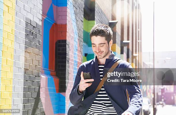 man smiling and walking in city with mobile - in motion stock pictures, royalty-free photos & images