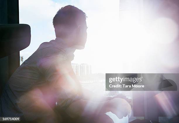 silhouette of man looking out window with flare - sun flare foto e immagini stock