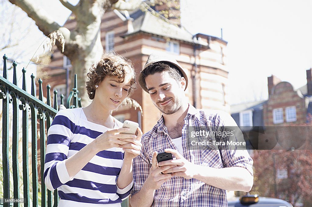 Man and woman with mobile phones outside