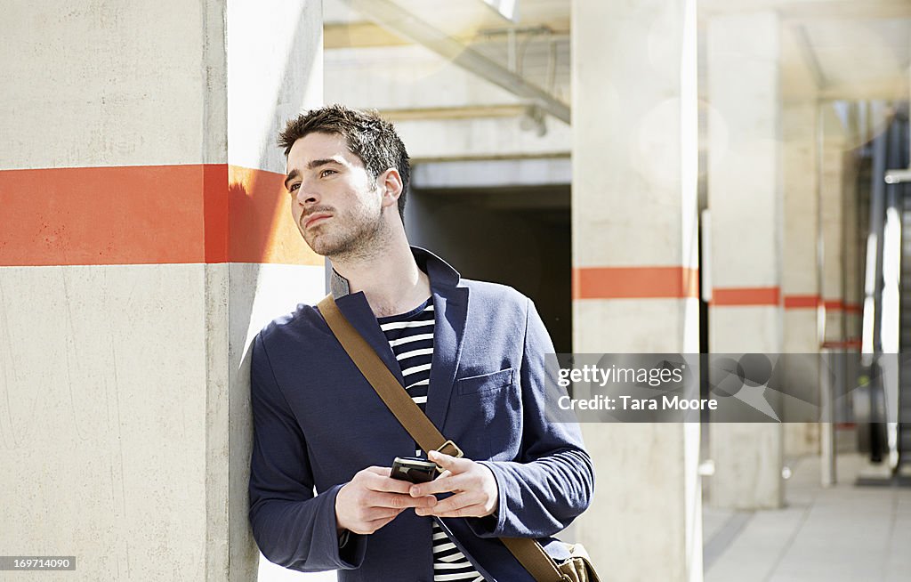 Man waiting at train station holding mobile