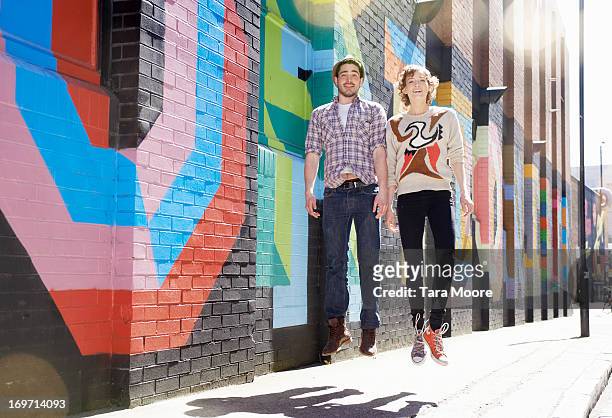man and woman jumping in street - london graffiti stock pictures, royalty-free photos & images