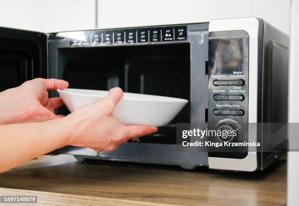 putting a bowl into a microwave - monoculture stock pictures, royalty-free photos & images
