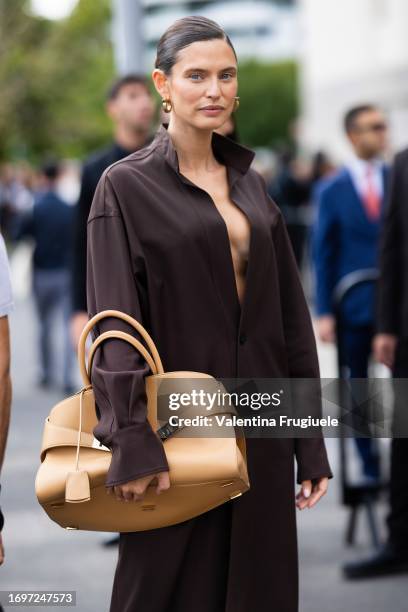 Bianca Balti is seen wearing gold hoop earrings, a light beige leather Ferragamo bag with gold hardware and a brown long shirt outside the Ferragamo...