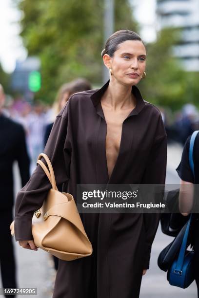 Bianca Balti is seen wearing gold hoop earrings, a light beige leather Ferragamo bag with gold hardware and a brown long shirt outside the Ferragamo...