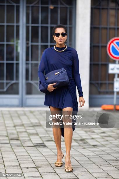 Tamu Mcpherson is seen wearing blue sunglasses, gold heels with chain applications on, a blue Ferragamo handbag, a gold necklace, gold hoop earrings...