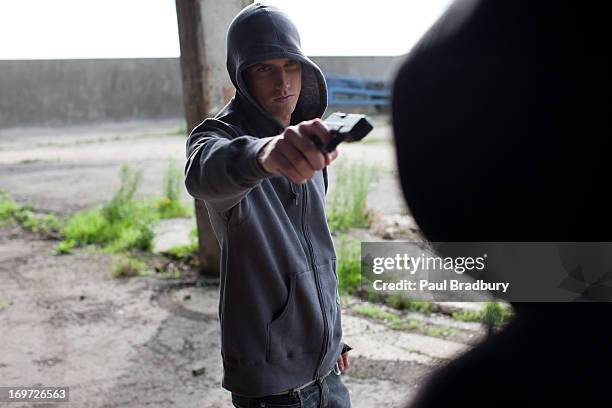 mann punkt waffe in nichts nachstehen - hooligan stock-fotos und bilder