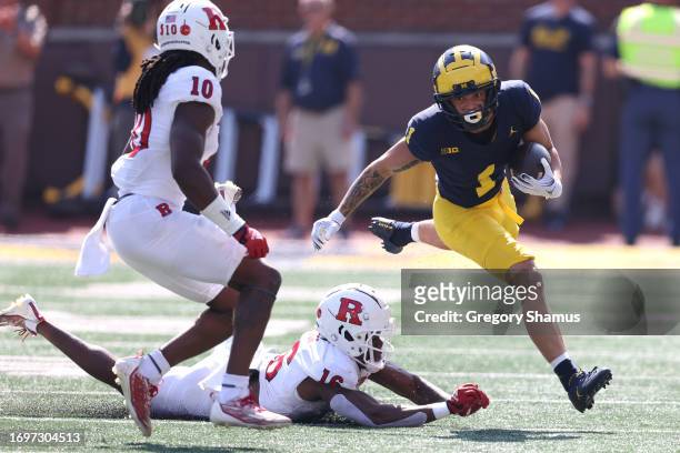 Roman Wilson of the Michigan Wolverines looks for yards after a first half catch against Max Melton and Flip Dixon of the Rutgers Scarlet Knights at...