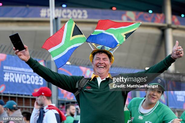 Fan of South Africa poses for a photograph, whilst wearing a builders hat decorated with National Flags of South Africa, on the outside of the...