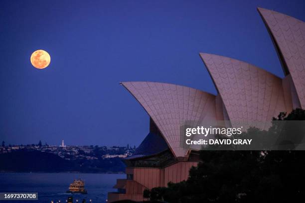 The full moon, a supermoon also known as the "Harvest Moon", rises above Macquarie Lighthouse and the Sydney Opera House in Sydney on September 29,...