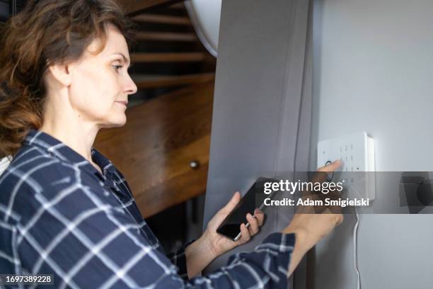 woman installing and setting up a home security system - burglar alarm stock pictures, royalty-free photos & images