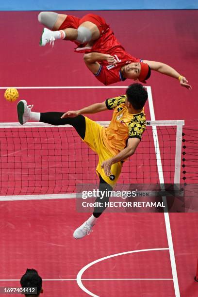 Thailand's Varayut Jantarasena kicks the ball as Malaysia's Mohamad Azlan Bin Alias defends in the men's team final of the sepak takraw event during...