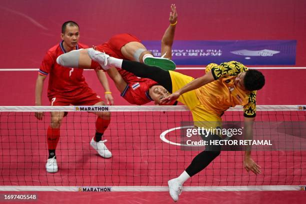 Thailand's Varayut Jantarasena kicks the ball as Malaysia's Mohamad Azlan Bin Alias defends in the men's team final of the sepak takraw event during...