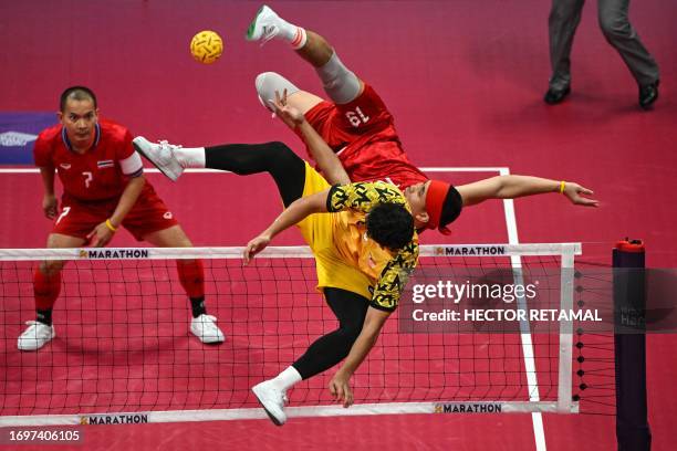 Thailand's Varayut Jantarasena kicks the ball as Malaysia's Mohamad Azlan Bin Alias defends in the men's team final of the sepak takraw event during...