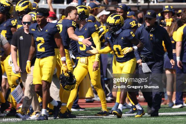 Mike Sainristil of the Michigan Wolverines celebrates his second half interception for a touchdown with teammates while playing the Rutgers Scarlet...