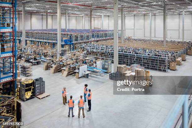 mujer mayor discutiendo el trabajo con el equipo de trabajadores en el almacén - fábrica fotografías e imágenes de stock