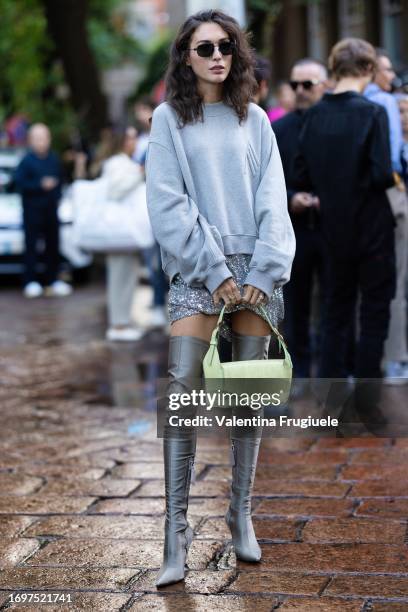 Diletta Bonaiuti is seen wearing a silver paillettes mini skirt, high grey boots and wide grey sweater outside The Attico show during Milan Fashion...