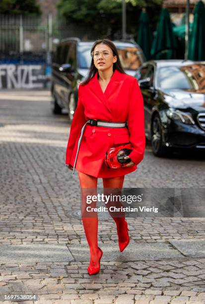 Guest wears red car bag, belt, red blazer, tights outside Ferrari during the Milan Fashion Week - Womenswear Spring/Summer 2024 on September 23, 2023...