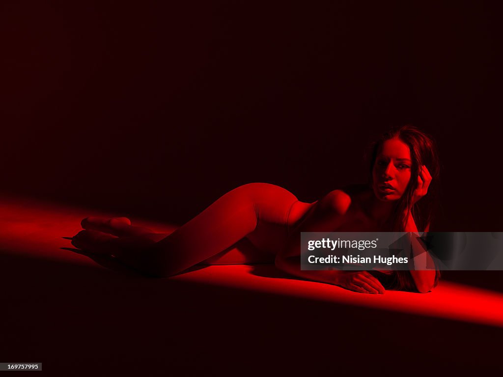 Beautiful woman laying down under red light