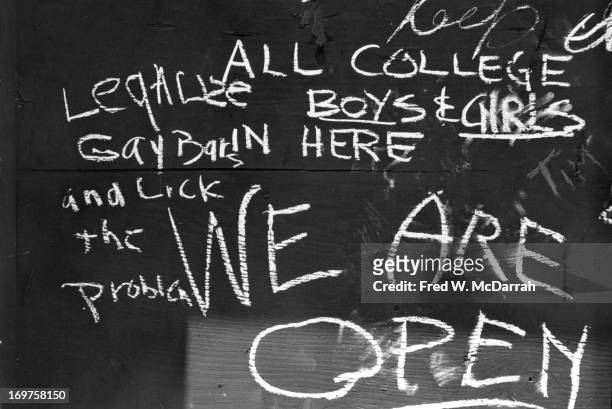 Close-up of handwritten chalk text on a boarded-up window of the Stonewall Inn after riots over the weekend of June 27, 1969. The text reads 'We Are...