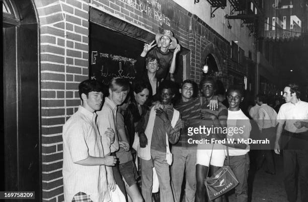 An unidentifed group of young poeple celebrate outside the boarded-up Stonewall Inn after riots over the weekend of June 27, 1969. The bar and...