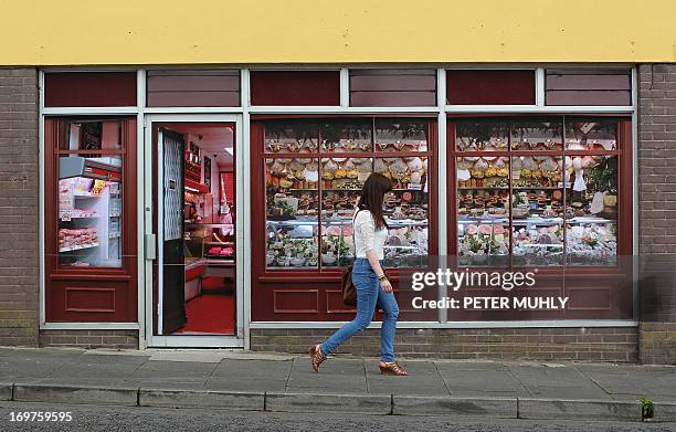 Pedestrian walks pass stickers applied to the windows of a former butcher’s shop in Belcoo, Northern Ireland, outside Enniskillen on June 1, 2013....