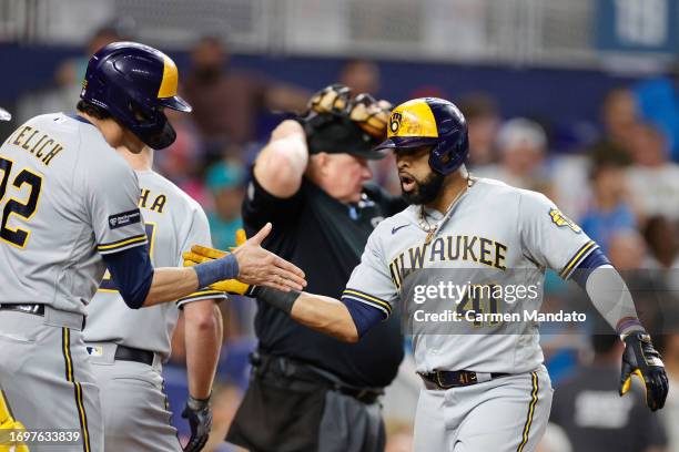 Carlos Santana of the Milwaukee Brewers high fives Christian Yelich after hitting a three run home run during the sixth inning against the Miami...