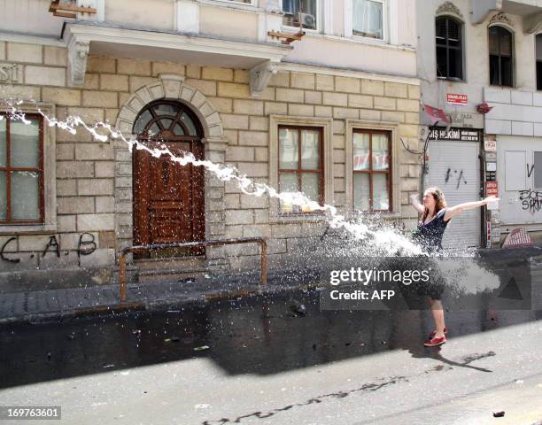 Woman opens her arms as police use a water cannon to disperse protestors on June 1, 2013 during a protest against the demolition of Taksim Gezi Park...