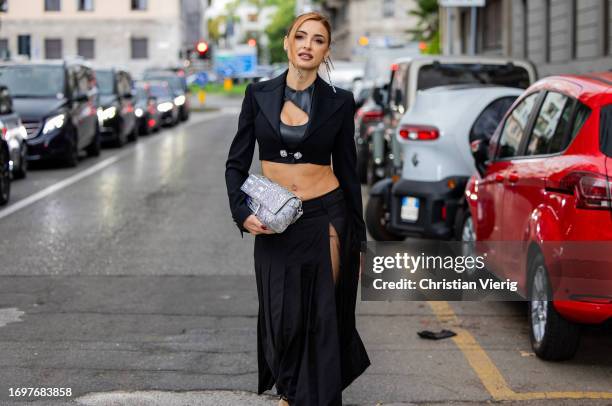 Guest wears black cropped top, transparent skirt with slit outside Dolce & Gabbana during the Milan Fashion Week - Womenswear Spring/Summer 2024 on...