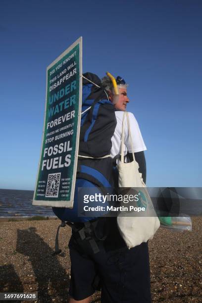 Dr Charlie Gardner wears a sign on his backpack warning of the danger of rising sea levels during a walk to highlight climate change on September 29,...
